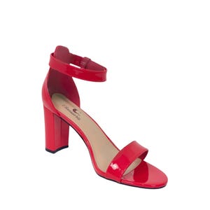 May include: Red patent leather heeled sandals with an ankle strap. The sandals have a block heel and the brand name "Classics" is printed on the insole.