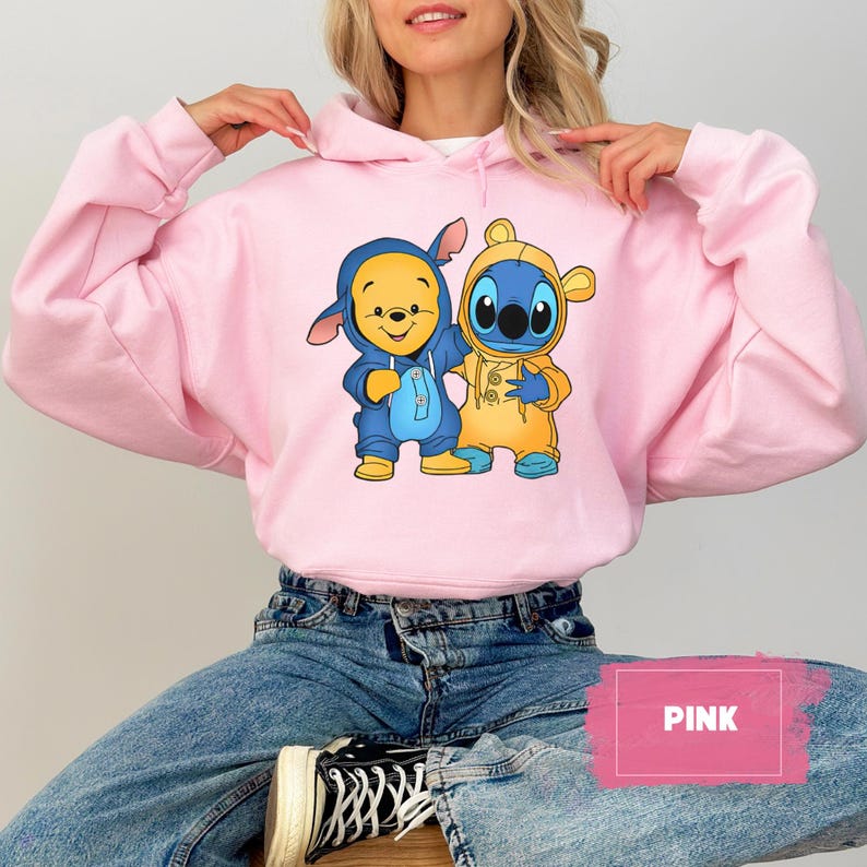 May include: A pink hoodie with a graphic of Winnie the Pooh and Stitch wearing matching outfits. The hoodie has a drawstring hood and a kangaroo pocket. The text "PINK" is visible in the lower right corner of the image.