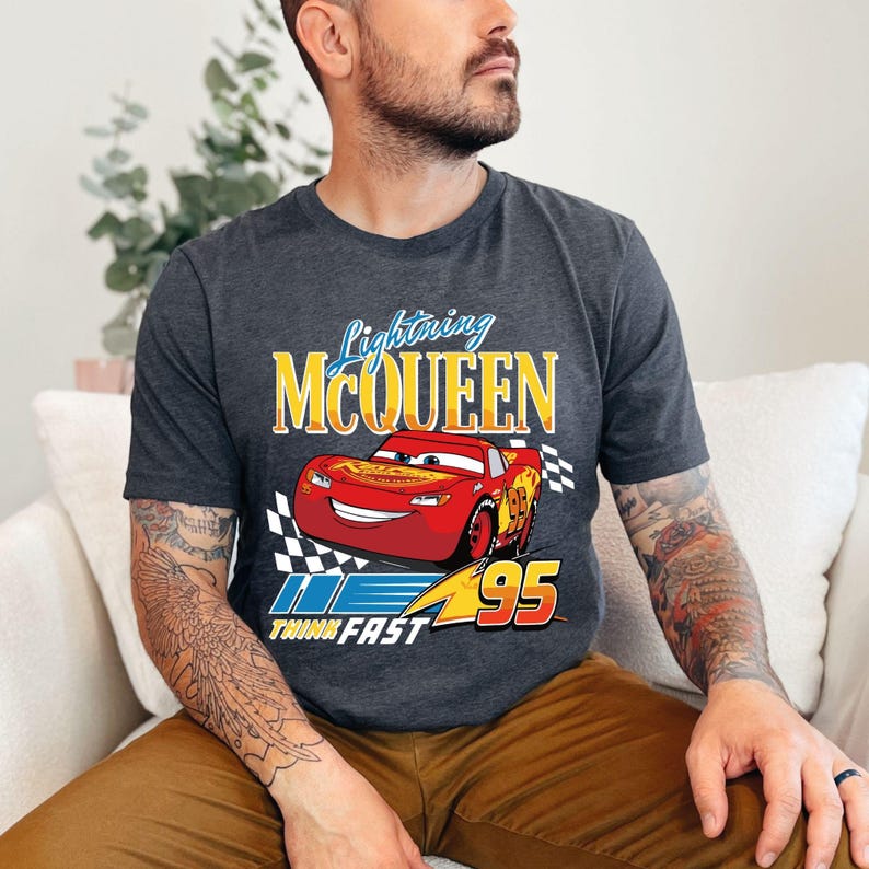 Puede incluir: Camiseta gris oscuro con Lightning McQueen de la pel&iacute;cula Cars. El dise&ntilde;o incluye un coche de carreras rojo con el n&uacute;mero 95, el texto "Lightning McQueen" y "Think Fast". La camiseta tiene cuello redondo cl&aacute;sico.