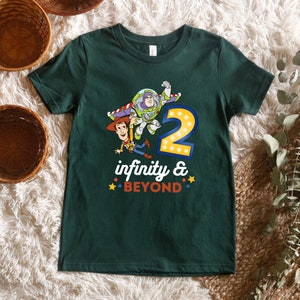 Puede incluir: Una camiseta verde con un gr&aacute;fico de Woody y Buzz Lightyear de Toy Story. El gr&aacute;fico incluye el n&uacute;mero "2" con luces y el texto "infinity & BEYOND".
