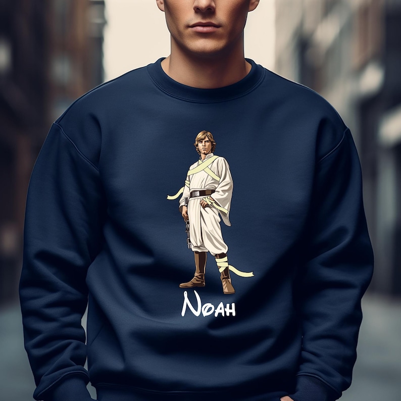May include: Navy blue sweatshirt featuring a stylized illustration of a character in a white outfit with a yellow sash. The character is standing with a weapon. The name "Noah" is written in white script below the character.