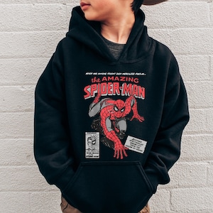 May include: Black hooded sweatshirt featuring a comic book graphic of Spider-Man. The graphic includes the text "the AMAZING SPIDER-MAN" in red and white, with additional text and illustrations.