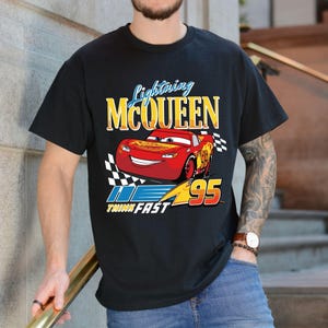 Puede incluir: Camiseta negra con un dise&ntilde;o de Rayo McQueen de la pel&iacute;cula Cars. El dise&ntilde;o incluye el texto "Lightning McQueen" en amarillo y el n&uacute;mero "95". Tambi&eacute;n se incluye la frase "Think Fast".