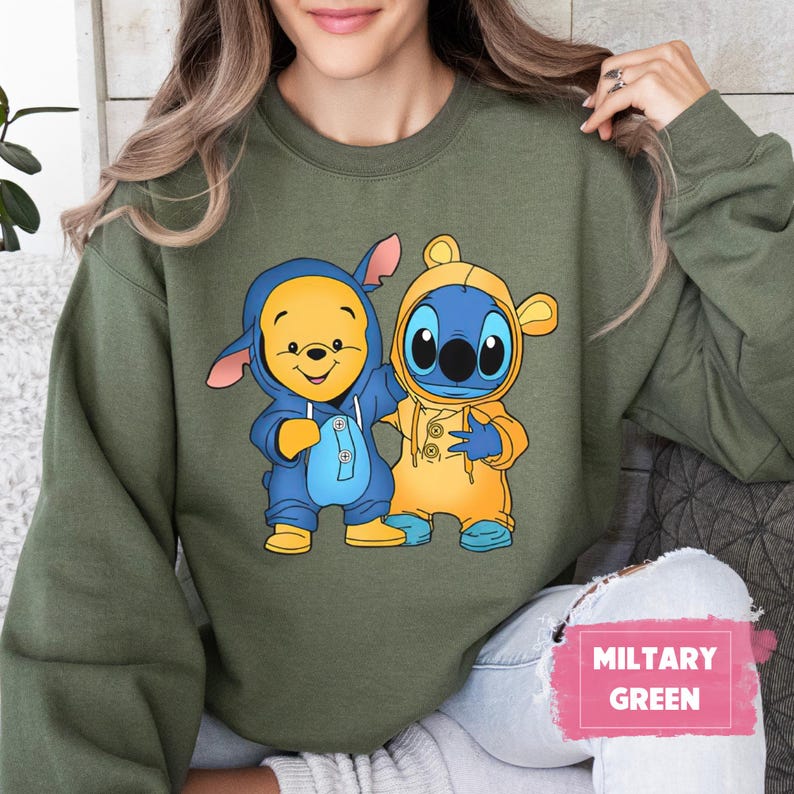 May include: A green sweatshirt with a cartoon image of Winnie the Pooh and Stitch wearing raincoats. The text "MILITARY GREEN" is in the lower right corner of the image.
