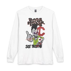 Può includere: Una maglietta bianca a maniche lunghe con la grafica di uno scheletro con cresta, che indossa una maglia verde e fa il dito medio. Il testo recita BASS NEVER DIES e JUST TRUST ME in nero e rosso, con una lettera C rossa e note musicali.