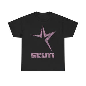 Puede incluir: Camiseta negra con un diseño de estrella rosa desgastada y la palabra "SCUTI" en una fuente a juego. El gráfico tiene un aspecto vintage y desgastado. Una prenda casual.
