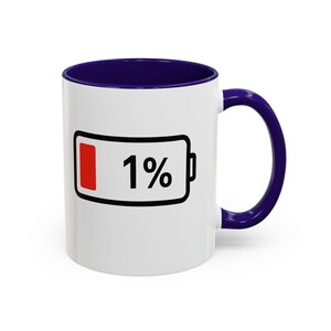 May include: White ceramic mug with a dark blue handle and interior. The mug features a black outline of a battery with a red fill at 1% and the number 1 in black.