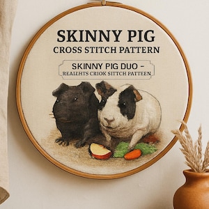 Può includere: Un modello a punto croce rotondo in un telaio di legno presenta due porcellini d'India, uno nero e uno bianco con segni neri. Il testo "SKINNY PIG CROSS STITCH PATTERN" è in alto. Una piccola fetta di mela e una carota sono in basso.