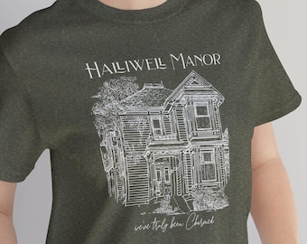 Puede incluir: Una camiseta verde oscuro con un gráfico blanco de una casa y el texto "Halliwell Manor" y "we've truly been blessed".