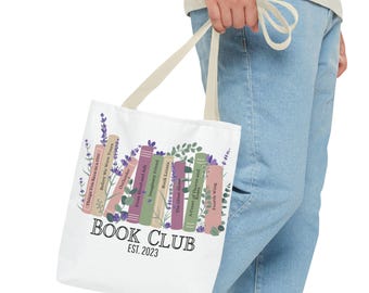 Pode incluir: Sacola de tecido branca com um design de clube do livro. A sacola apresenta uma pilha de livros com títulos como "Outlander", "Imaginary Friend" e "The Great Alone". A sacola também tem ilustrações de lavanda e vegetação. O texto "BOOK CLUB EST. 2023" está impresso na sacola.