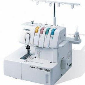 May include: White Brother Coverstitch 1034D sewing machine with four spools of thread in yellow, pink, blue, and white. The machine has a clear plastic cover over the needle area and a white plastic foot pedal.