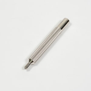 May include: A silver-colored metal tool with a textured, diamond-patterned grip. The tool has a cylindrical body that tapers to a pointed tip. The tool is designed for precision work and is set against a white background.