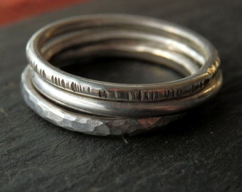 May include: Three silver rings stacked on top of each other. The top ring has an inscription that reads "I had you first".