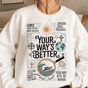 Op de afbeelding: Witte sweatshirt met een grafisch ontwerp met de tekst "Your Way's Better" en andere religieuze zinnen. Het ontwerp bevat kruisen, een wereldbol, een zon en een jetski in een vergrootglas.
