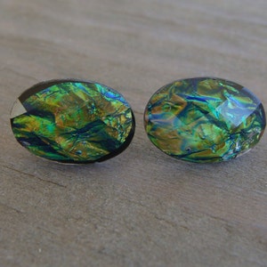 May include: A pair of oval-shaped earrings with a green, blue, and gold iridescent finish.