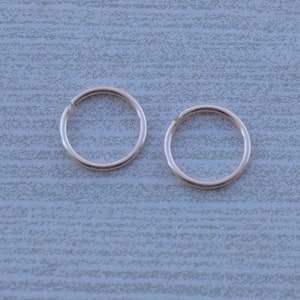 May include: Two silver hoop earrings, each with a simple circular design.