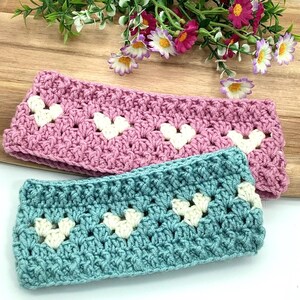 K&ouml;nnte beinhalten: Zwei geh&auml;kelte Stirnb&auml;nder mit wei&szlig;en Herzmotiven. Ein Stirnband ist rosa und das andere ist t&uuml;rkis.