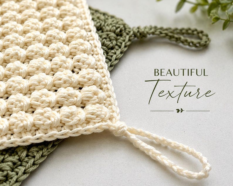 May include: Close-up of two handmade crochet washcloths. One is cream-colored with a textured, raised pattern and a loop for hanging. The other is olive green with a simple stitch pattern. The words "BEAUTIFUL Texture" are written in script.