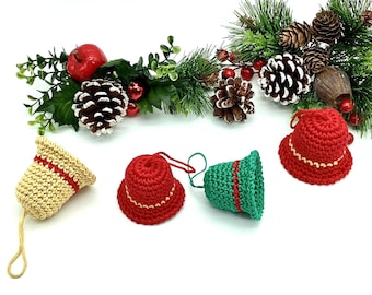 May include: A collection of handmade crochet Christmas ornaments. The ornaments include three red bell-shaped ornaments, one green bell-shaped ornament, and one beige ornament with red stripes. Decorative pinecones, berries, and greenery are in the background.