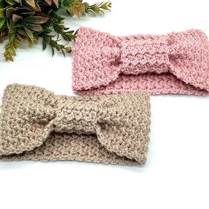 May include: Two handmade crochet headbands. One is light pink, the other is tan. Both headbands have a textured stitch and a bow detail at the centre. The headbands are displayed on a white surface.