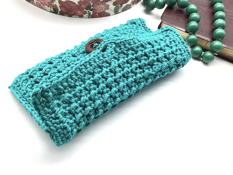 May include: A teal crocheted clutch with a wooden button closure.