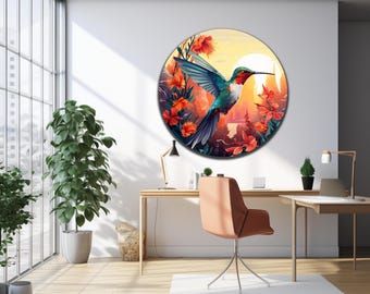 May include: A circular wall art piece featuring a vibrant hummingbird in flight surrounded by bright orange and red flowers against a sunset background with a large white sun, displayed on a plain white wall above a wooden desk and chair.