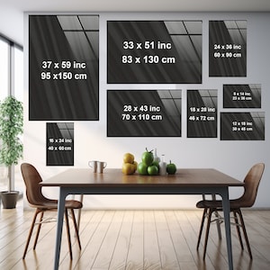 May include: A mock-up of a dining room with a wooden table and chairs. The wall behind the table is decorated with eight framed prints of abstract black and white images. The prints are of various sizes and are arranged in a staggered pattern. The text on the prints includes the dimensions of the prints in inches and centimeters.
