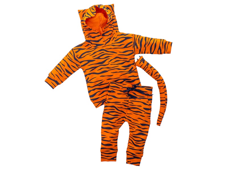 May include: Orange and black tiger print hooded sweatshirt and matching pants with a tail. The set is made for a baby or toddler.
