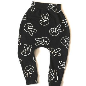 Puede incluir: Pantalones negros y blancos con un dise&ntilde;o de signo de paz. Los pantalones est&aacute;n hechos de una tela suave y c&oacute;moda y tienen un ajuste holgado.