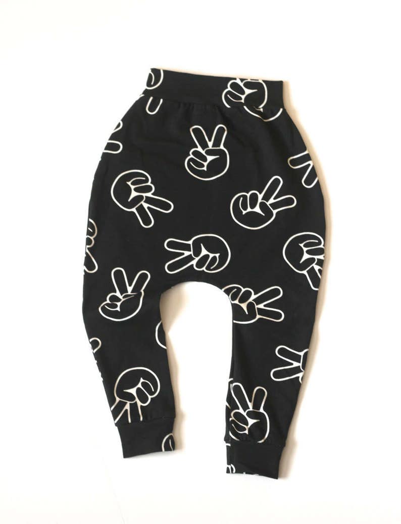 Puede incluir: Pantalones negros y blancos con un dise&ntilde;o de signo de paz. Los pantalones est&aacute;n hechos de una tela suave y c&oacute;moda y tienen un ajuste holgado.