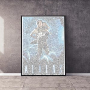 Op de afbeelding: Een ingelijste poster met de filmtitel "ALIENS" in witte hoofdletters. De poster toont een scène uit de film met twee figuren. De poster staat tegen een grijze betonnen muur en vloer.