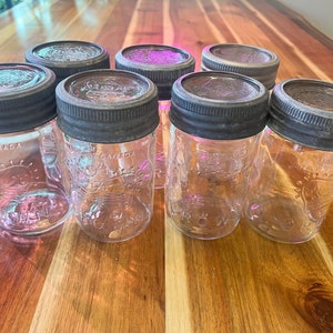 May include: Eight clear glass jars with metal lids. The jars have a vintage look and are labelled with the text "MADE IN CANADA" and "CROWN".