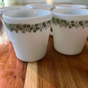 以下が含まれることがあります： 緑色の花柄が上部の縁に施された白いセラミック製のマグカップ6個セットです。