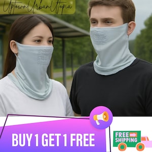Puede incluir: Dos personas con cubiertas faciales y de cuello de color azul claro. Las cubiertas tienen un diseño cuadrado en la parte delantera. La imagen también contiene el texto "Uptown Urban Utopia" y "BUY 1 GET 1 FREE".