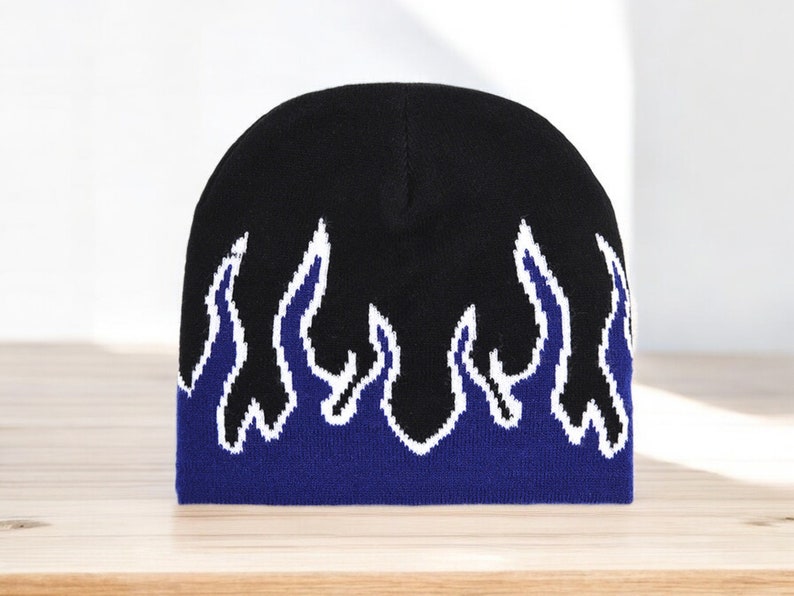Puede incluir: Gorro negro con un dise&ntilde;o de llamas azules y blancas.
