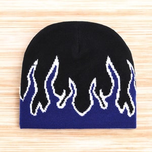 Puede incluir: Gorro negro con un dise&ntilde;o de llamas azules y blancas.