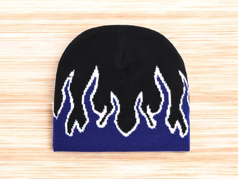 Puede incluir: Gorro negro con un dise&ntilde;o de llamas azules y blancas.