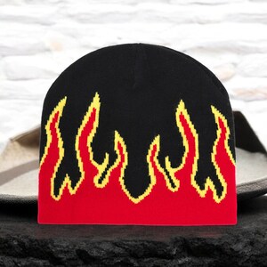 Puede incluir: Gorro negro con llamas rojas y amarillas tejidas en el dise&ntilde;o.