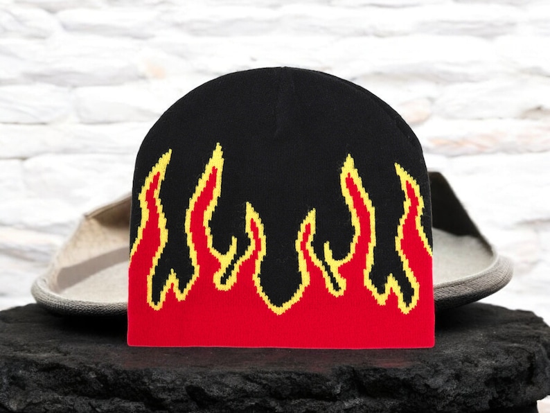 Puede incluir: Gorro negro con llamas rojas y amarillas tejidas en el dise&ntilde;o.
