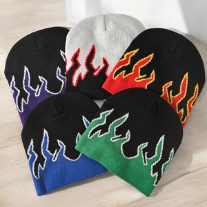 Puede incluir: Seis gorros de punto con dise&ntilde;os de llamas en diferentes colores. Los gorros son negros, blancos, rojos, verdes, azules y morados. Las llamas est&aacute;n bordadas en amarillo, rojo y blanco.