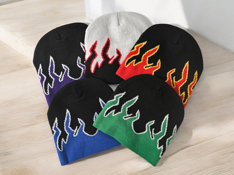 Puede incluir: Seis gorros de punto con dise&ntilde;os de llamas en diferentes colores. Los gorros son negros, blancos, rojos, verdes, azules y morados. Las llamas est&aacute;n bordadas en amarillo, rojo y blanco.