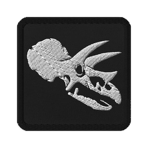 May include: A white embroidered patch on a black background featuring a dinosaur skull with three horns.