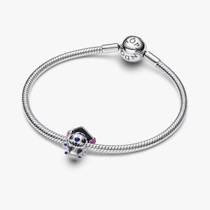 May include: A silver snake chain bracelet featuring a round clasp engraved with the word PANDORA. A charm shaped like a blue and purple character wearing a black graduation cap is threaded onto the bracelet, adding a distinct decorative element.