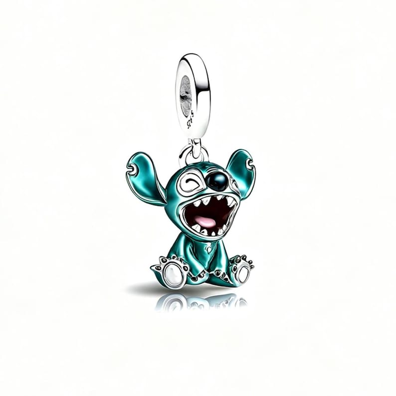 May include: A sterling silver charm featuring a teal enameled character with large ears, a wide open mouth, and white accents on the feet. The charm includes a circular bail at the top with the S925 hallmark clearly visible on the side of the metal.