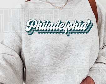May include: A gray sweatshirt with a teal green retro-style graphic that says "Philadelphia".