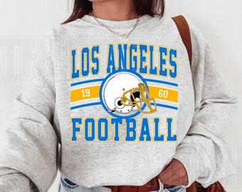 Op de afbeelding: Grijs sweatshirt met de tekst "Los Angeles Football" in blauwe en gele letters. Een voetbalhelm-afbeelding is gecentreerd boven de tekst.