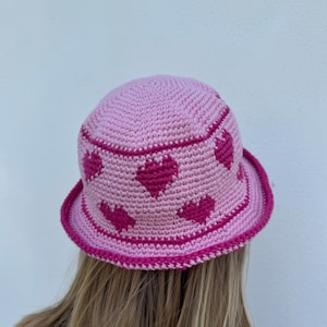 May include: A pink crocheted bucket hat with a pink and white heart pattern.