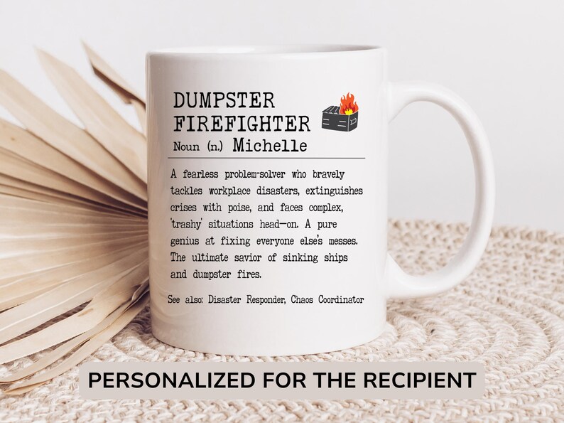 May include: White ceramic mug with a black and white design that reads "DUMPSTER FIREFIGHTER Noun (n.) Michelle A fearless problem-solver who bravely tackles workplace disasters, extinguishes crises with poise, and faces complex, 'trashy' situations head-on. A pure genius at fixing everyone else's messes. The ultimate savior of sinking ships and dumpster fires. See also: Disaster Responder, Chaos Coordinator PERSONALIZED FOR THE RECIPIENT"