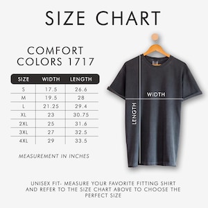 Peut inclure: Un tableau des tailles pour les t-shirts Comfort Colors 1717. Le tableau affiche les mesures en pouces (converties en cm) pour les tailles S &agrave; 4XL, y compris la largeur et la longueur. Un t-shirt gris est suspendu &agrave; un cintre en bois.