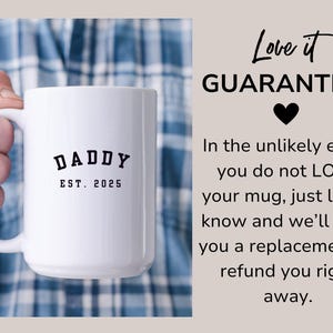 May include: White ceramic mug with a black inscription that reads "DADDY EST. 2025". The mug is being held by a hand wearing a plaid shirt. The text "Love it GUARANTEE!" is written in black on a light brown background.